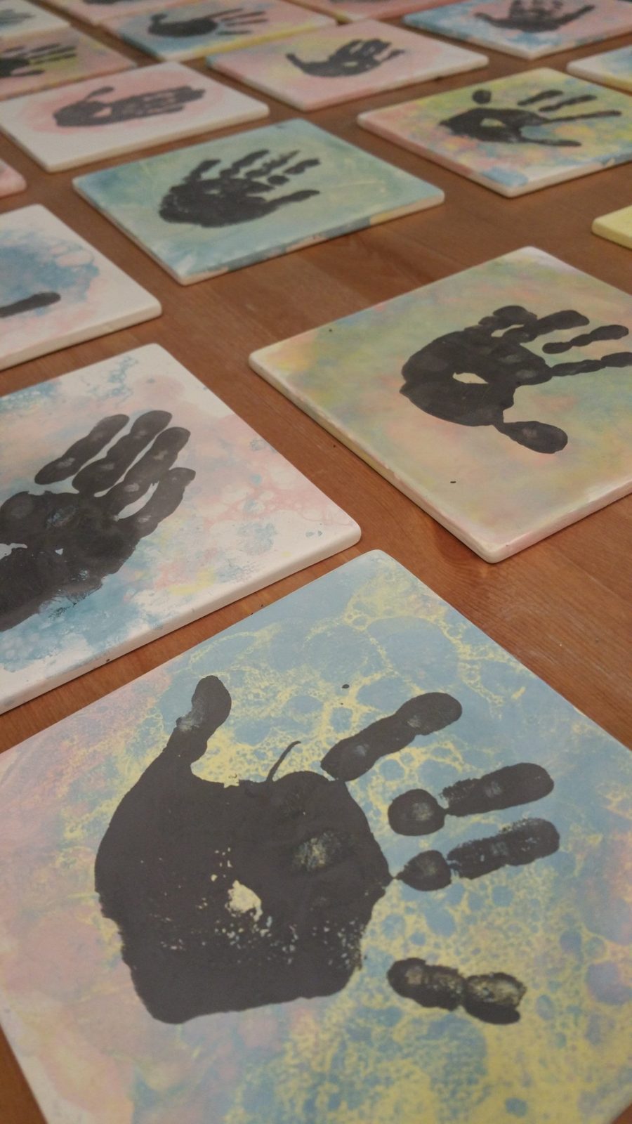 A wall of colorful handprint tiles painted by studio guests